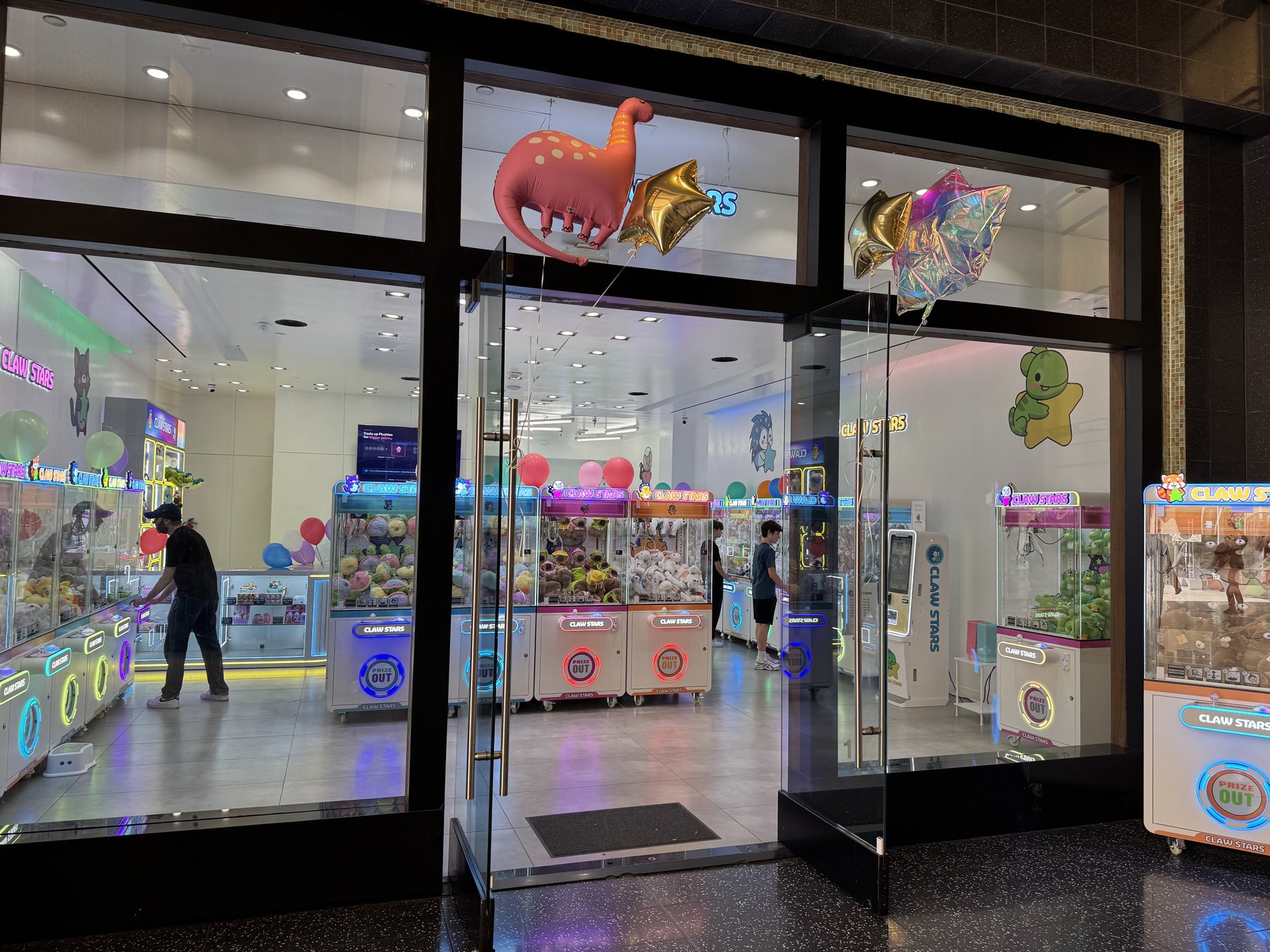 Claw Stars storefront in Ovation Hollywood with pink dinosaur and gold star balloons floating in front